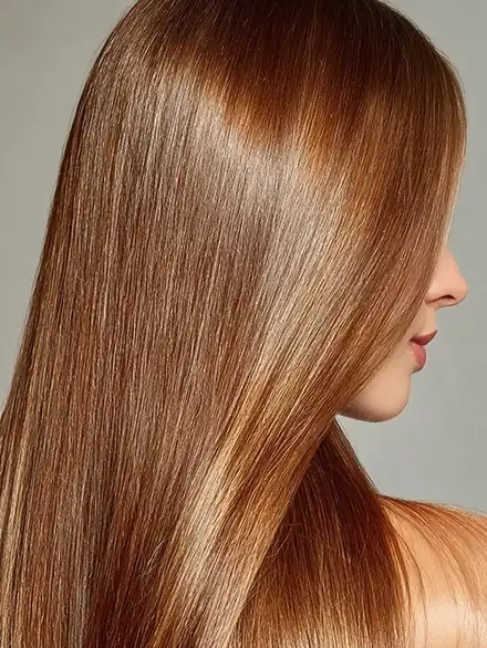 Cabello cobrizo con reflejos dorados, liso y con brillo intenso, visto de perfil